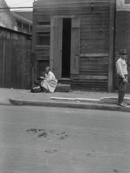 Woman sitting on steps holding a basket, New Orleans, between 1920 and 1926. Creator: Arnold Genthe