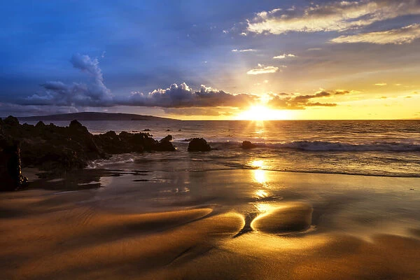 A golden sunset with reflection on sand at on an empty beach, Maui, Hawaii, USA