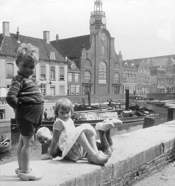 Historic image in black and white of children playing together along the canal in the Netherlands, circa 1900; Delfthaven, Holland