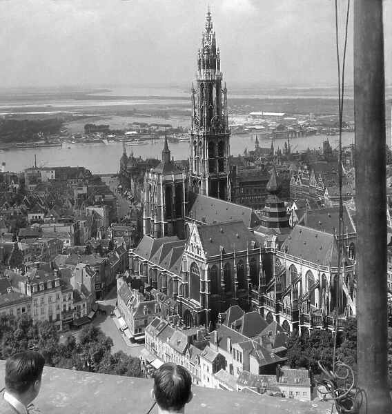 Historic image in black and white of people viewing landmarks from a rooftop, Cathedral of our Lady and the Scheldt River in Antwerp; Antwerp, Belgium