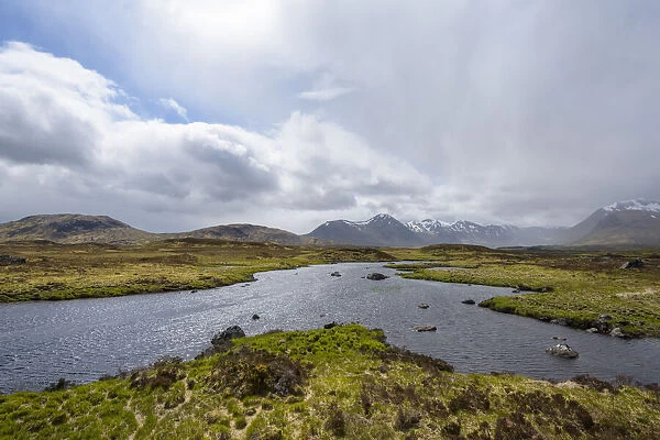 Moor landscape with a river and the sun shining through the cloudy sky at Rannoch Moor in Scotland, United Kingdom