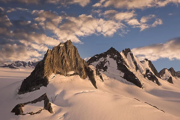 Mountain peaks rise through the snowy glaciers of the Juneau Ice Field at sunset, Alaska, USA