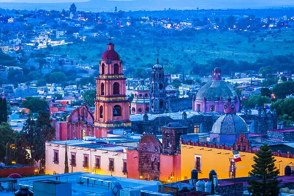The pink stone bell tower of the Oratorio de San Felipe Neri and overview of the city at dusk in San Miguel de Allende, Mexico