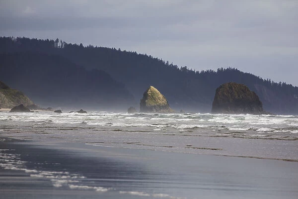 Rock Formations In The Ocean With Waves On The Beach; Cannon Beach, Oregon, United States of America