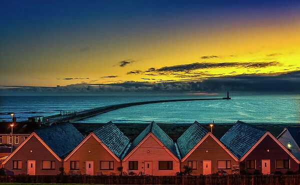 Row of Houses illuminated at sunset with Roker Pier Lighthouse in the distance, Sunderland, England