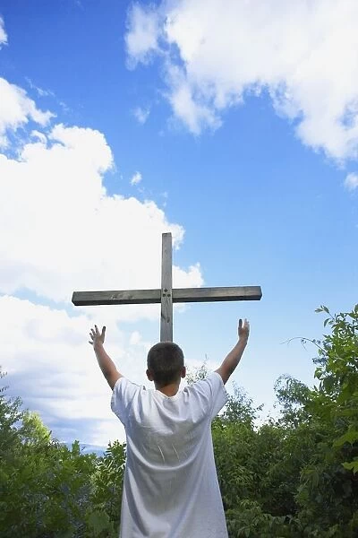 A Teenage Boy With Arms Raised Towards The Cross
