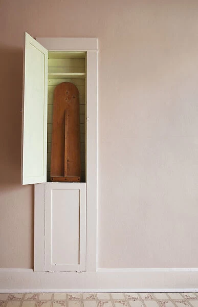 A wooden ironing board in a cupboard in the wall; Parkland county alberta canada