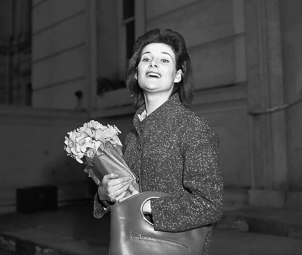 Actress Adrienne Corrie holding a bunch of flowers April 1956