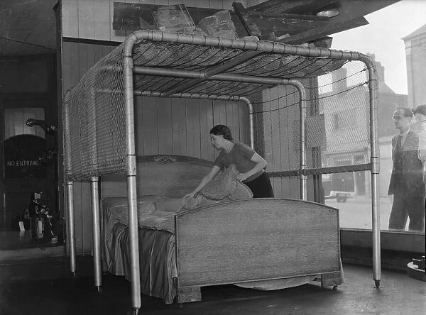 Birmingham furniture store displays in its shop window, a bed air raid protection frame