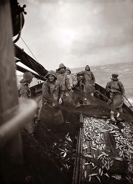 The crew of a Yarmouth Herring boat pull in their catch on a storm tossed North Sea