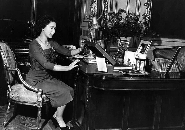 Queen Elizabeth II at her desk in Buckingham Palace looking through her correspondence