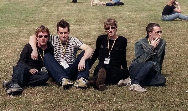 Travis at T in the Park sitting on the grass 2 members are smoking July 1999