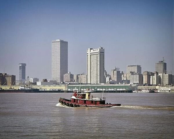 1970s CENTER CITY SKYLINE WITH TUG BOAT ON MISSISSIPPI RIVER IN FOREGROUND NEW ORLEANS LOUISIANA USA - kr28018 GRD001 HARS EDIFICE MUDDY WATERFRONT