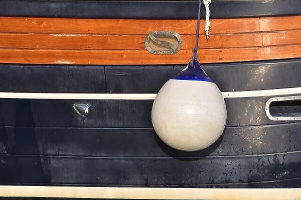 A Fender (boating) hanging on the board to protect the side of the sailing vessel from the damage. Italy
