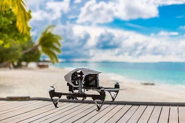 Flying drone with mounted camera at the beach. Palm trees and blue lagoon