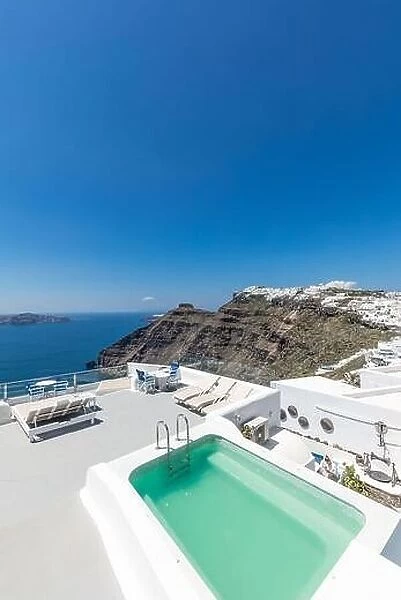 Scenic view of traditional cycladic resort with Jacuzzi in foreground, Oia village, Santorini, Greece. Luxury summer travel destination, vibes, mood