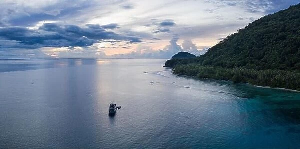 A small dive boat is anchored off the coast of Papua New Guinea. This tropical area is part of the Coral Triangle due to its high marine biodiversity