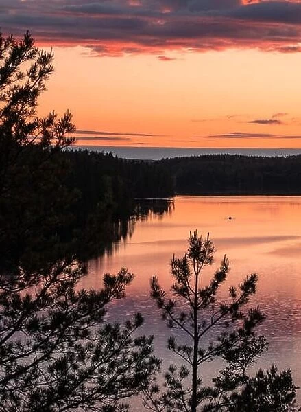 Sunset landscape with peaceful lake and row boat at summer night in Finland