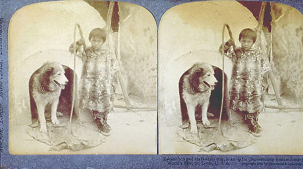 Eskimo child, in ethnic clothes, with a husky dog in front of the entrance of an igloo. The child has a whip in his hand