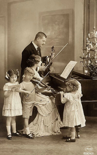 Family portrait while playing music with violin and piano where is laying the Christmas tree, Christmas post-card