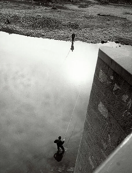 Two fishermen, photographed from above, while fishing on the bank of a river