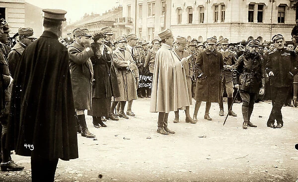 An Italian army officer speaks to a group of people in a square of Fiume. Among them, Gabriele D'Annunzio is recognizable. The photograph was taken during the occupation of city by part of the Italian legionary troops, headed by the poet