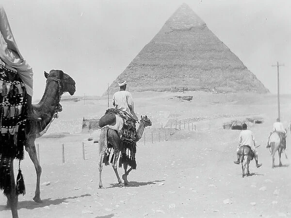 Men with donkeys and dromedaries in front of the Pyramid of Cheops or Great Pyramid of Giza, Egypt