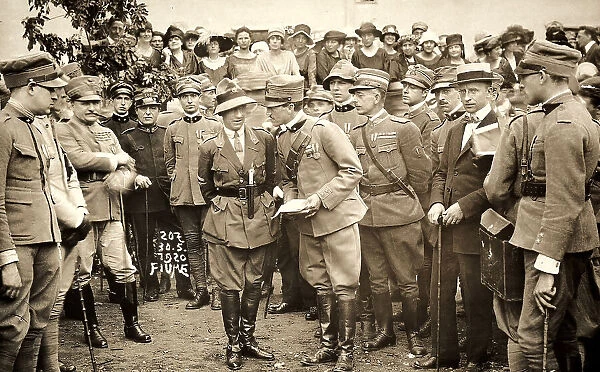 A military officer addresses some soldiers. The photograph was taken after the occupation of Fiume, headed by Gabriele D'Annunzio. In the background, a group of civilians
