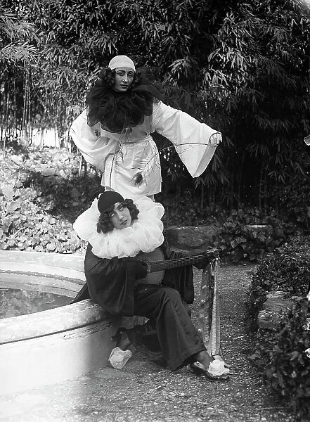 Portrait of two fancy dressed young women posing near a fountain