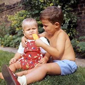 Little boy and baby in garden with ice lolly
