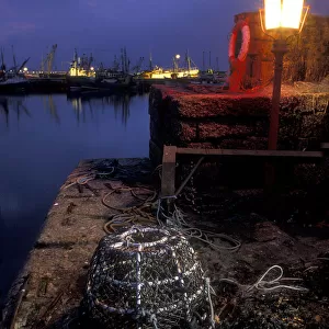 Lobster pot lit by harbour light at night, Newlyn, Cornwall