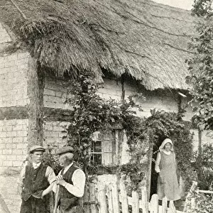 Men and woman outside a thatched cottage, Herefordshire