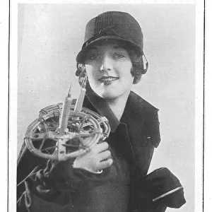 Model wearing a wool hat and holding ski-poles, with one mitten zipped. Date: 1930