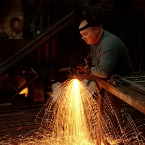 A steelworker makes a shower of sparks in his workshop