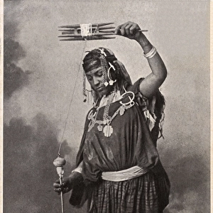A Tunisian Arab Woman spinning wool using a hand spindle