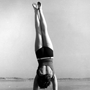 Woman doing handstand on beach
