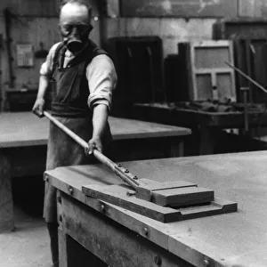 A workman smoothing the surface of the slate bed of a billiard table at a factory in