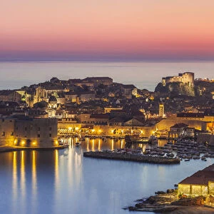 Aerial panorama of Dubrovnik Old Town at night with orange sunset sky, UNESCO World Heritage Site