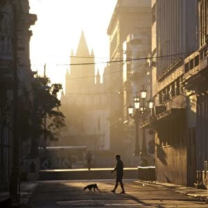 Backlit street at dawn with people in semi-silhouette, off Prado, Havana Centro, Havana, Cuba, West Indies, Central America