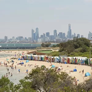 Beach scene with beach huts at Brighton Beach, Brighton, and in background skyscrapers of the city of Melbourne, Victoria