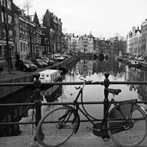 Black and white imge of an old bicycle by the Singel canal, Amsterdam, Netherlands
