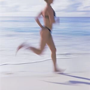 Blurred motion image of a woman jogging on the beach