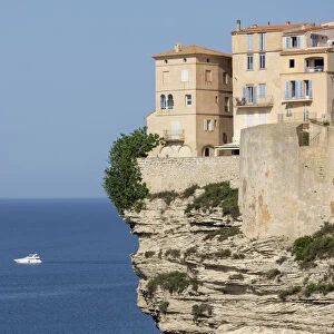 The Citadel and old town of Bonifacio perched on rugged cliffs with boat in the Mediterranean