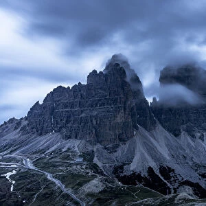 Clouds at dusk in the foggy sky over Tre Cime di Lavaredo mountain peaks, Dolomites, South Tyrol, Italy, Europe