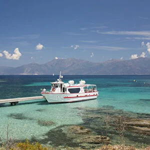 Excursion boat moored at jetty in clear turquoise water off the Plage du Loto, St-Florent, Haute-Corse, Corsica, France, Mediterranean, Europe