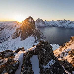First light of sunrise on Mount Segla and Mefjorden framed by the frozen sea seen from peak Hesten
