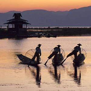 Three fishermen balance on one leg at sunset on Inle Lake, Shan State, Myanmar (Burma)