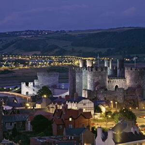Floodlit Conwy Castle, UNESCO World Heritage Site, overlooking the town with the River Conwy estuary beyond at dusk, Gwynedd, North Wales, United