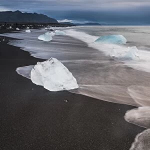 Icebergs at sunrise on Jokulsarlon Beach, a black volcanic sand beach in South East Iceland