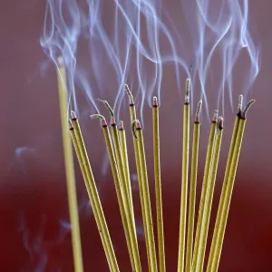 Incense sticks on joss stick pot burning, smoke used to pay respect to the Buddha